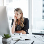 her workload is weighing heavy on her mind. a young businesswoman experiencing stress while working at her desk in a modern office.